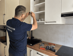 Handwerker bei Kleinreparatur in moderner Kuche in Wien mit Werkzeug und Akkuschrauber