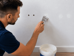 Handwerker spachtelt Dübellöcher und repariert Wand für Wohnungsübergabe in Wien